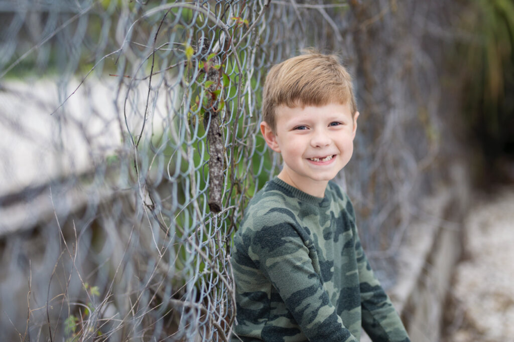 boy leaning against chain link fence